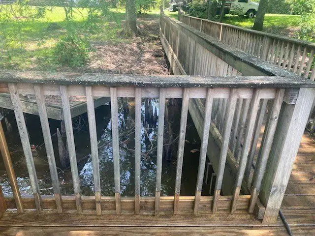 Before, a bayou-side handrail under algae and weathering